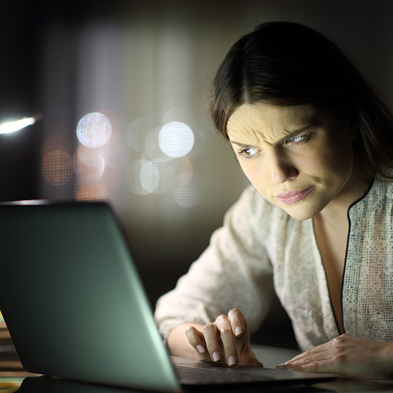 Vrouw kijkt argwanend naar laptop door phishing