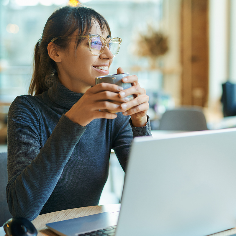 Lachende vrouw met laptop en een tas koffie